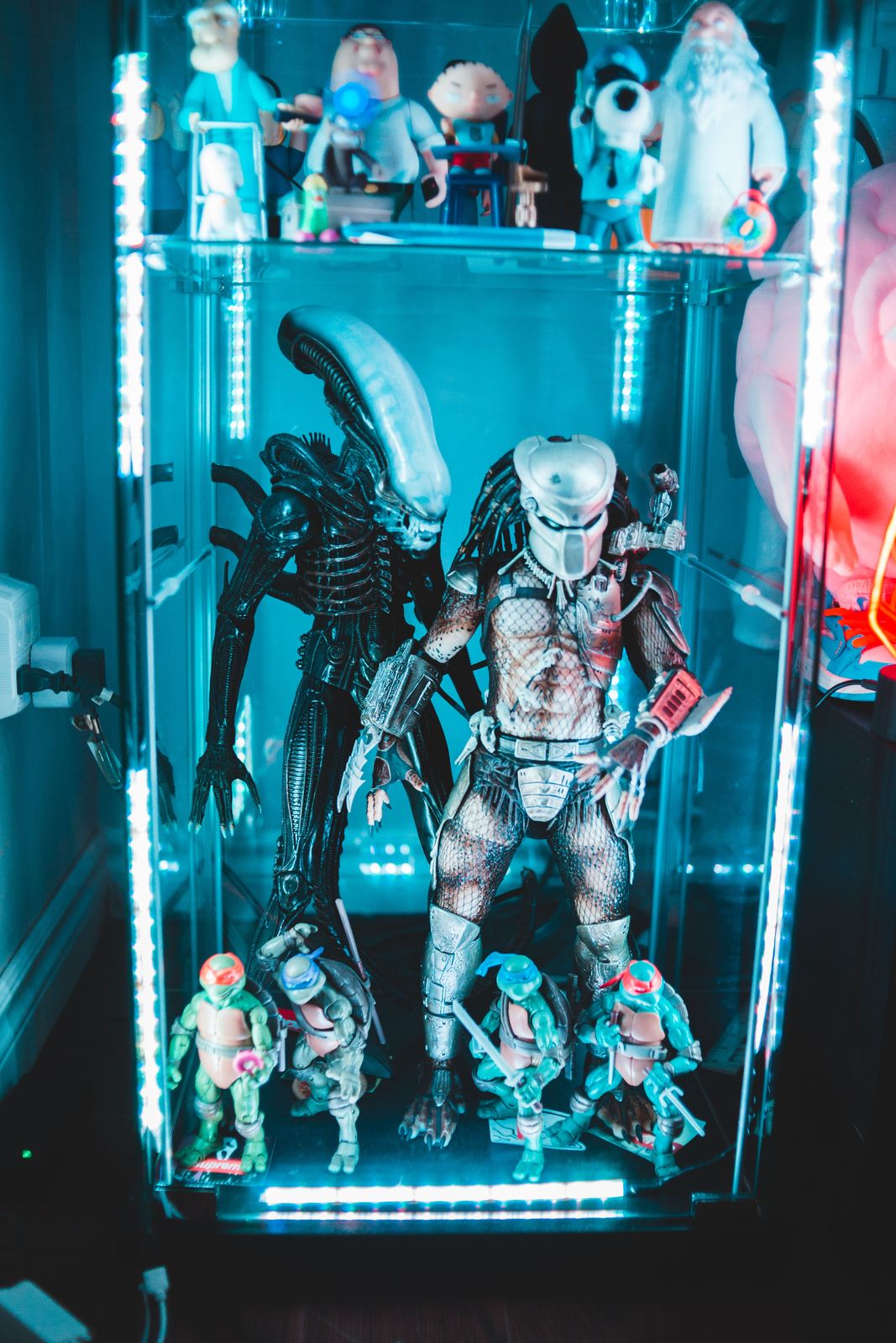 LED-lit glass cabinet holding large sci-fi creature action figures with four small turtle hero figures in front