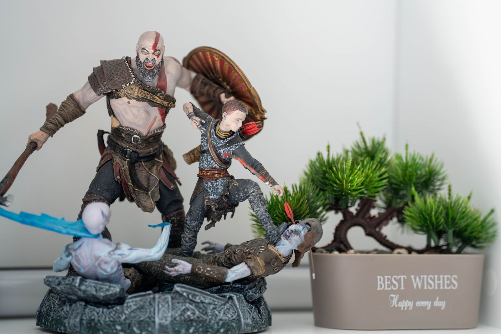 Battle diorama of a bearded warrior with axe and shield and a young archer standing over fallen enemies on a carved stone base